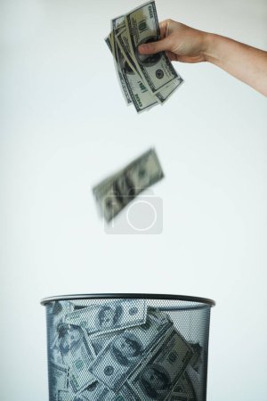 Photo for Dont throw your life savings away - Bank. Someone throwing money away in a trash can - Royalty Free Image