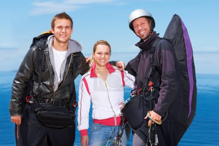 Photo for Ready for some paragliding. Three para gliders posing for the camera before their jump - Royalty Free Image
