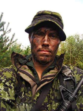 Photo for A tired look. Closeup of Yuri with facial camouflage sporting a rifle and wearing fatigues - Royalty Free Image