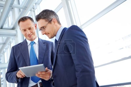 Foto de Aquí está mi propuesta corporativa. Vista recortada de dos hombres de negocios mirando una tableta digital juntos - Imagen libre de derechos