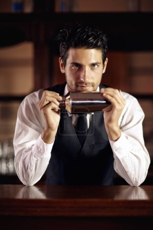 Photo for Shaken, not stirred. A handsome young bartender mixing a cocktail - Royalty Free Image