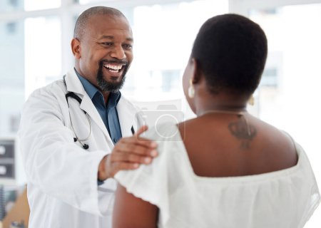 Photo for Cheerful doctor offering a patient support. Mature african american doctor touching a patient on the arm. Happy gp offering a patient comfort in a consult. Doctor talking to a patient. - Royalty Free Image