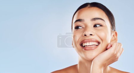 Photo for Closeup face beautiful young mixed race woman. An attractive female posing in studio isolated against a blue background. A skincare regime that keeps your skin soft, smooth, glowing and healthy. - Royalty Free Image
