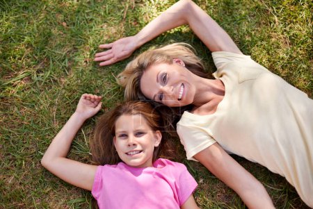 Photo pour Passer du bon temps avec maman. Une mère heureuse et sa jeune fille couchées sur l'herbe ensemble à l'extérieur et levant les yeux - image libre de droit