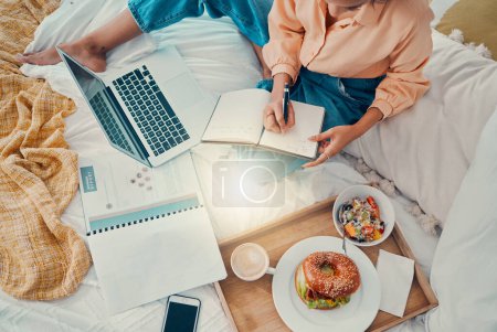 Marketing, Laptop und Frau schreiben mit Frühstück auf dem Bett, arbeiten und planen Strategieinformationen von oben. Remote-Mitarbeiter mit Notizen, Lebensmitteln und Berichten für kreatives Arbeiten am PC.