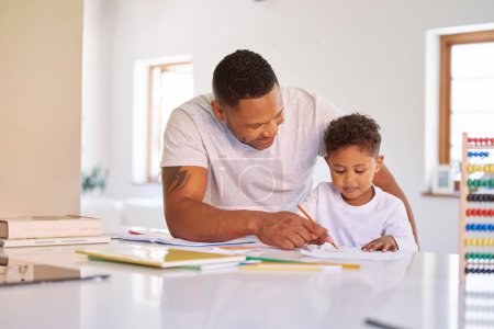 Foto de Mixed race boy learning and studying in homeschool with dad. Man helping his son with homework and assignments at home. Parent teaching child to colour and write at home during lockdown. - Imagen libre de derechos