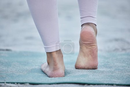 Frau im Yoga-Dehnfuß am Strand beim Beintraining in einer ganzheitlichen Fußübung oder beim Workout in der Natur. Fitness, Wellness oder spirituelles Zen-Girl-Training für Gleichgewicht oder gesunden, starken Körper allein.
