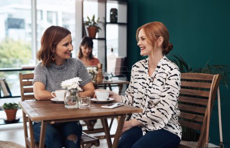 Foto de ¿Qué está pasando en tu vida? dos atractivas mujeres de mediana edad tomando un café juntos como amigos dentro de una cafetería durante el día - Imagen libre de derechos
