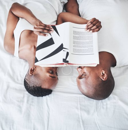 Foto de Eres mi cuento de hadas hecho realidad. una joven pareja leyendo un libro juntos en la cama en casa - Imagen libre de derechos