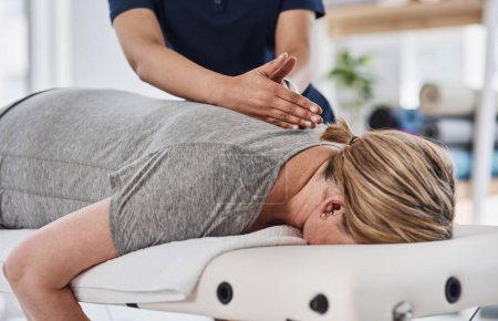 Votre dos a toujours besoin d'un traitement spécialisé. une femme mature allongée face contre terre et se faisant masser le dos par un physiothérapeute dans une clinique