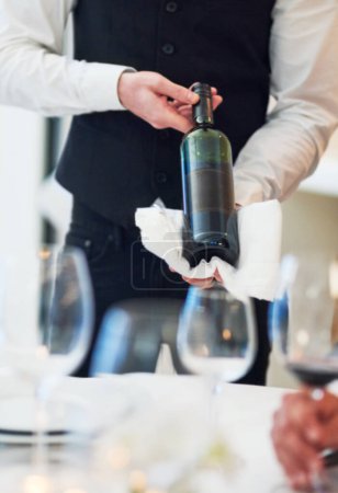 Foto de Creo que este es el vino que quieres. un camarero irreconocible sosteniendo una botella de vino en un restaurante - Imagen libre de derechos