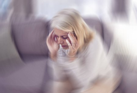 Photo for Senior woman, headache and sofa in home with motion blur, pain and depressed while tired in retirement. Elderly, old woman and anxiety with burnout, depression and panic attack on couch at house. - Royalty Free Image