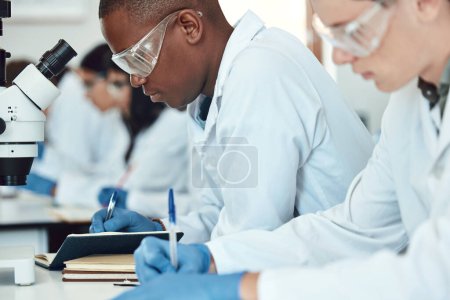 Science students, research and writing in laboratory, experiment and healthcare innovation. Researchers, notebooks and make notes for medical scientific methods, exams and analysis for cure and focus.