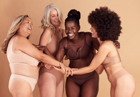 Photo pour Beauté, diversité et groupe de femmes en lingerie dans un studio isolé sur fond brun. Sous-vêtements, amis et femmes positives pour le corps, amour de soi et prise de main pour l'autonomisation, rire ou sourire. - image libre de droit