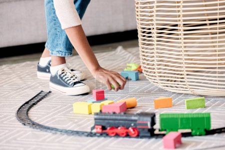 Photo for Mother, cleaner or babysitter woman hands cleaning kids toys and mess in a living room. Helping nanny or mom with care in a family house clean children play toy off the floor carpet in a home lounge. - Royalty Free Image