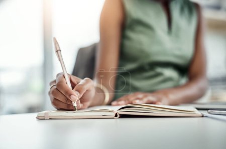 Diarizando eventos importantes. una joven empresaria irreconocible que escribe en su diario mientras trabaja en la oficina