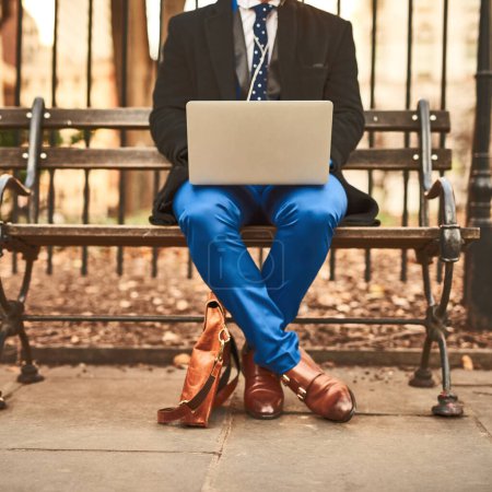 Immer arbeiten, egal wo. ein unkenntlich gemachter Mann arbeitet an seinem Laptop, während er tagsüber draußen auf einer Bank sitzt