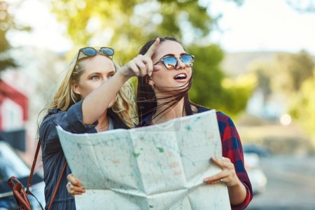 Photo for The map says we should go that way. two beautiful female friends looking at a map for directions in the city - Royalty Free Image
