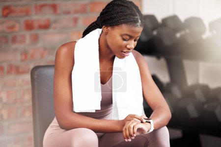 Photo for Fitness, health and black woman with smart watch in gym for tracking workout, exercise or progress. Sports, tech and female athlete with towel and watch to time training or record heart rate on break. - Royalty Free Image