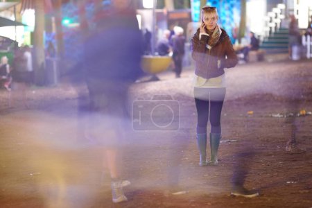 Hey, can you come pick me up. Young woman standing outside at night speaking on her cellphone - copyspace