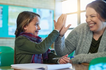 Photo for Becoming a top student with the help of her teacher. an elementary school girl high fiving her teacher in class - Royalty Free Image