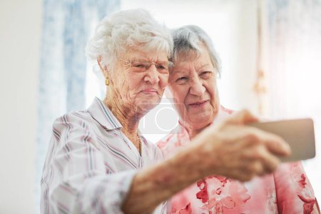Téléchargez les photos : C'est ce que les enfants appellent un selfie. deux femmes âgées heureuses prenant selfies ensemble sur un téléphone mobile - en image libre de droit