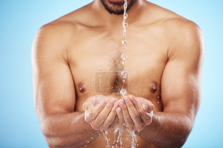 Mann, Wasser oder Händewaschen auf blauem Hintergrund für Körperhygiene, Gesundheit Wellness oder Hautpflege Routine. Modell, Wasserspritzer oder fließende Dusche zur Reinigung von Bakterien oder Selbstpflege.
