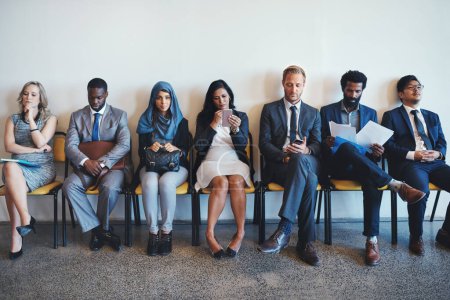 Photo for They have waited a long time for this. a group of confident businesspeople waiting in line for their interviews inside of a office during the day - Royalty Free Image