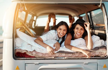 Photo for Chilling out, road trip style. two happy friends relaxing on a blanket in the true of their van on a road trip - Royalty Free Image