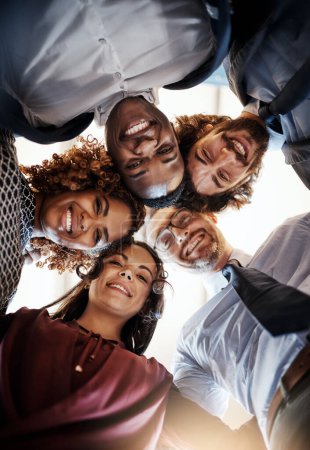 Photo for Its important to have a team you can trust. Low angle portrait of a team of happy businesspeople putting their heads together in a huddle - Royalty Free Image