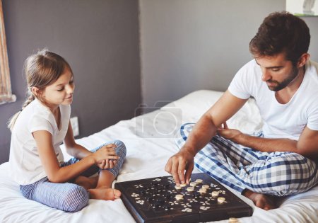 Photo for Making the next move. a young father playing a board game with his adorable little daughter at home - Royalty Free Image