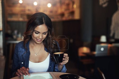 Photo pour Le café a meilleur goût avec un côté de wifi. une jeune femme détendue utilisant sa tablette dans un café - image libre de droit