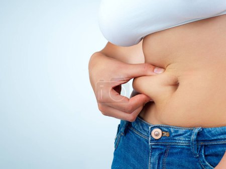 Una libra a la vez. una joven no identificable pellizcando un rollo de grasa en su estómago en el estudio