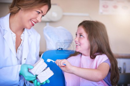 Foto de Evite la pérdida permanente de dientes y la caries dental. una dentista enseñando a su joven paciente a cepillarse los dientes - Imagen libre de derechos