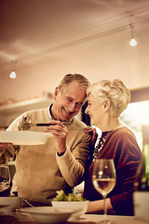 Photo for Its your favourite, sweetheart. an elderly couple dishing up a meal in their kitchen at home - Royalty Free Image