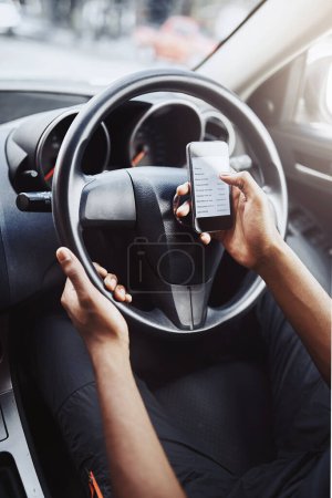 Foto de No te distraigas en la carretera. un hombre irreconocible usando su teléfono mientras conduce un coche - Imagen libre de derechos