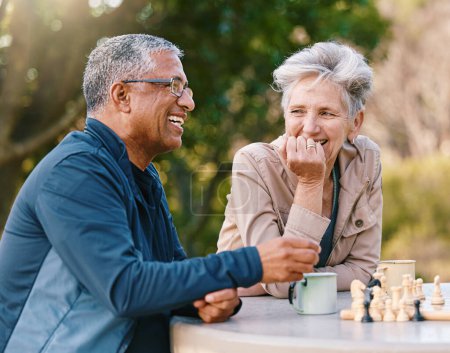 Happy, chess or couple of friends in nature playing a board game, bonding or talking about a funny story. Park, support or healthy senior people laughing at a joke and enjoying quality relaxing time.