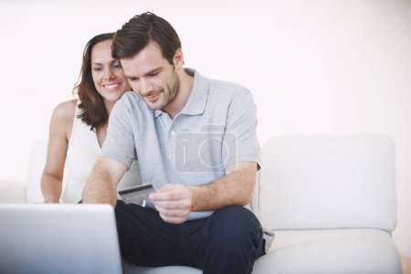 Paying those bills before theyre due. A young man paying bills online while his wife sits beside him