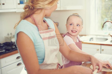 Foto de Hornear es muy divertido. Linda niña horneando en la cocina con su mamá - Imagen libre de derechos