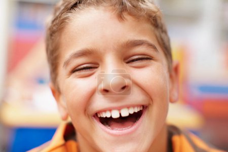 Téléchargez les photos : Une exubérance juvénile. Gros plan d'un jeune garçon heureux riant à haute voix directement à la caméra - en image libre de droit