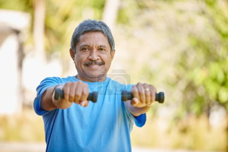 Foto de Mantenerse fuerte y en forma. Retrato de un hombre maduro levantando pesas afuera - Imagen libre de derechos