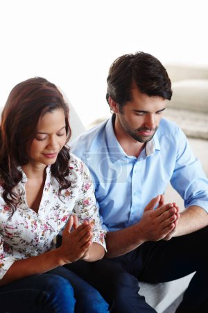 Téléchargez les photos : This relationship is strengthened by our faith. A young couple sitting together in prayer - en image libre de droit