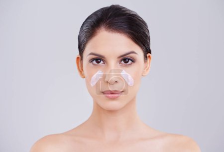 Photo for Looking after her skin. a beautiful young woman with moisturizer on her face - Royalty Free Image