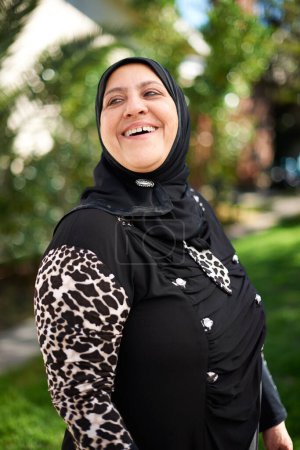 Téléchargez les photos : Living life with laughter. Portrait of a mature muslim woman standing outside - en image libre de droit