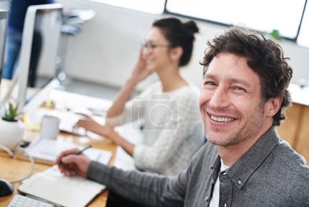 Photo pour Make creativity a job. Portrait of a smiling office worker and his coworker sitting at their desks - image libre de droit