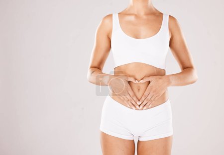 Foto de Health, body and hands in heart of a woman with lose weight results, fitness and beauty goals on studio white background. Underwear, skincare and model woman with gut health, stomach and diet mockup. - Imagen libre de derechos