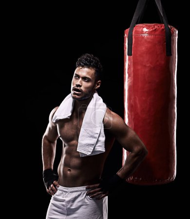 Photo for Time to hit the showers. Studio shot of kick boxer working out with a punching bag against a black background - Royalty Free Image