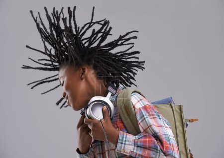 Téléchargez les photos : Whipping his dreads. A black teen listening to music over his headphones - en image libre de droit