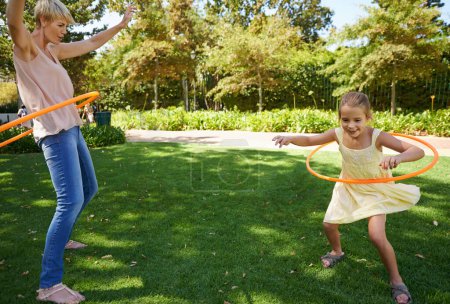 Photo for Shes a natural. A happy young mother and daughter hula hooping in the park on a sunny day - Royalty Free Image