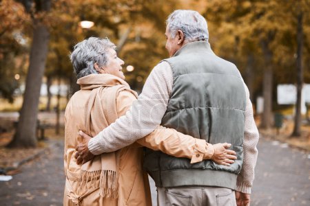 Foto de Senior couple, love and health while walking outdoor for exercise, happiness and care at a park in nature for wellness. Old man and woman embrace in a healthy marriage during retirement with freedom. - Imagen libre de derechos